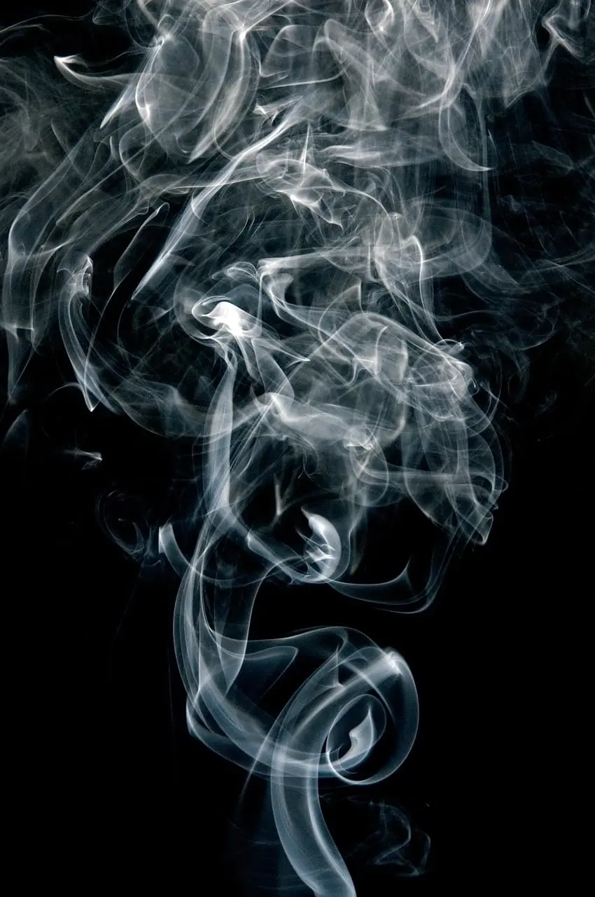 Wisps of white smoke curling and dispersing against a black background